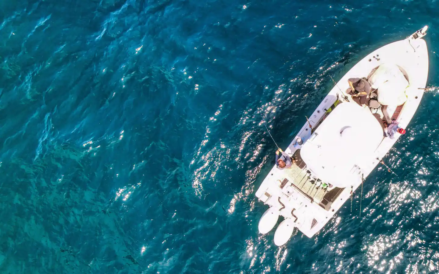 Aerial view of a center console fishing boat with rods out on deep blue water