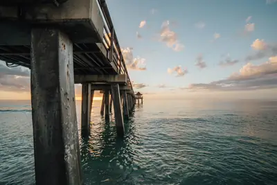 Sunset over calm Gulf water seen from under the Naples Pier